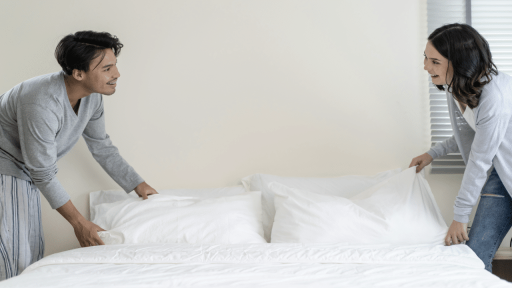 A couple fixing their bed in the morning