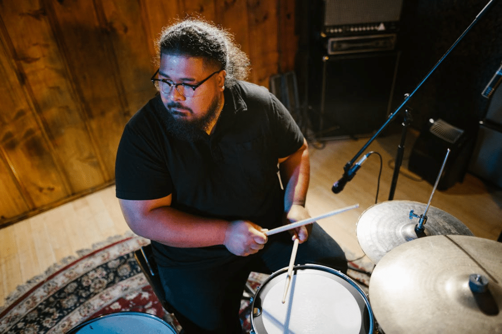 High-Angle Shot of a Man in Black Polo Shirt Playing Drums