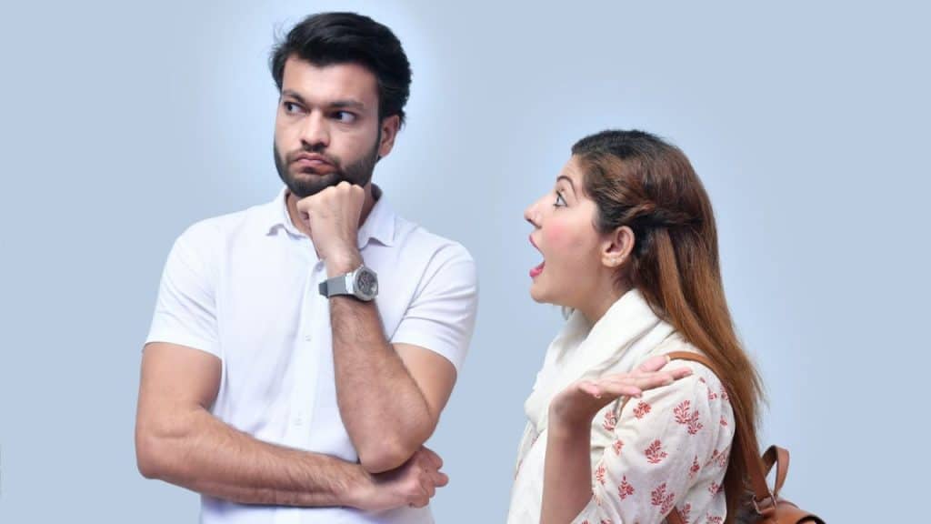 Man with a beard looks away in thought while a woman with long hair gestures excitedly.