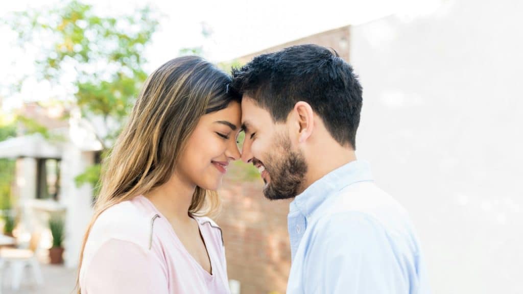 Smiling couple forehead-to-forehead outdoors.