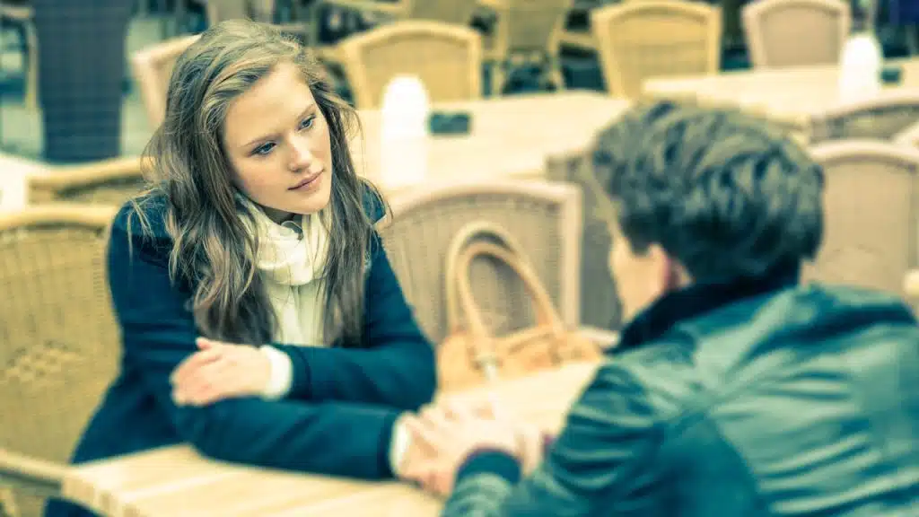 Woman intently listening to a blurred person across a cafe table.