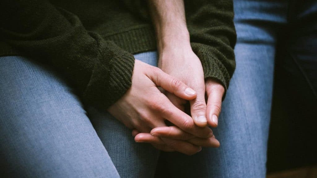 A close-up of two people holding hands while sitting.