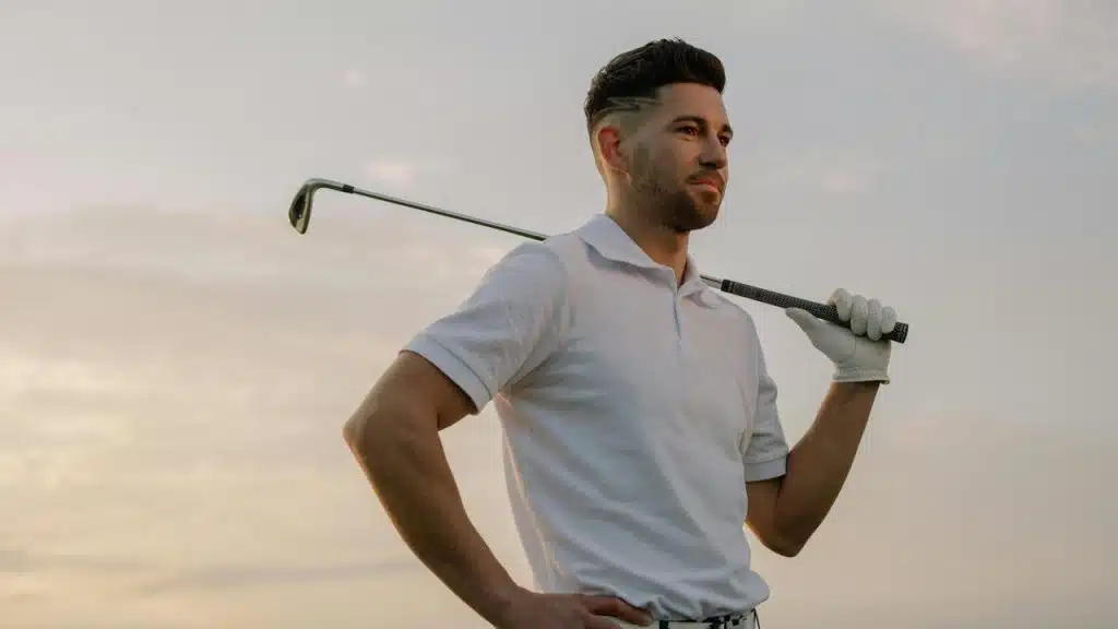A man in a white polo shirt holding a golf club over his shoulder.