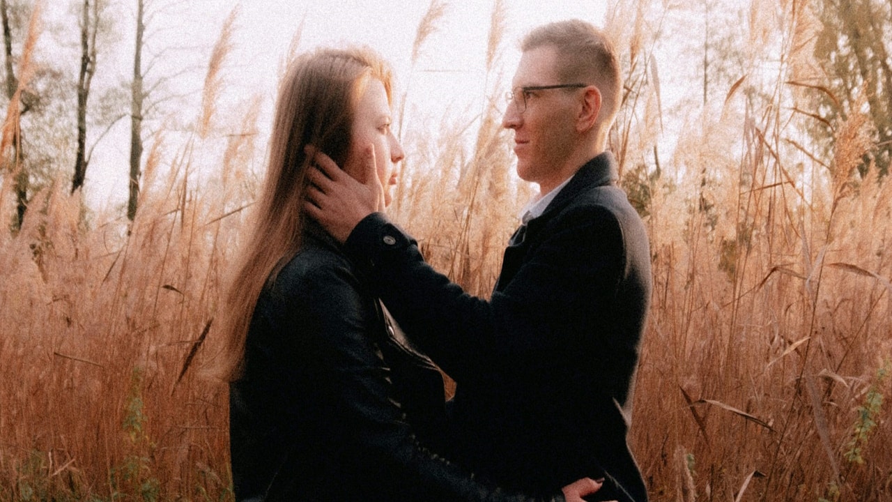 A sad couple standing in tall grass.
