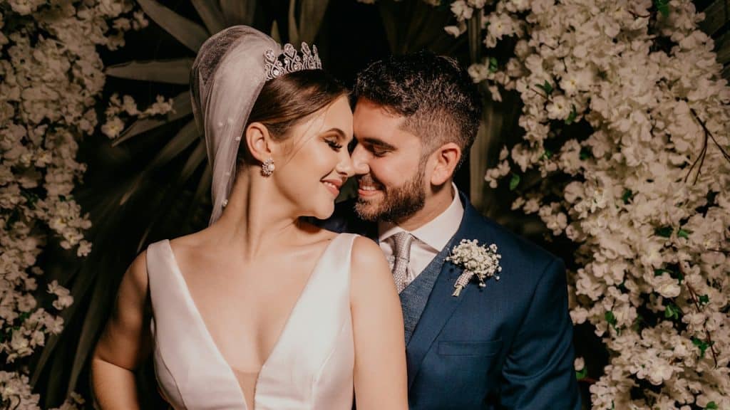 A happy bride and groom touching their noses with their eyes closed.