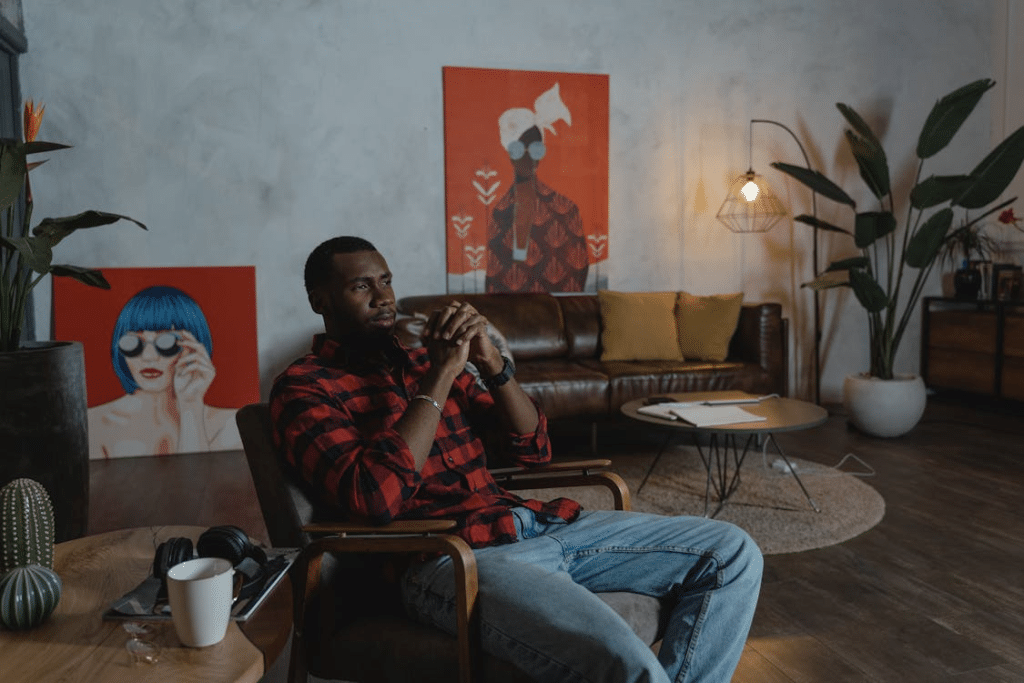 Man in Black and Red Striped Long Sleeve Shirt Sitting on Brown Chair