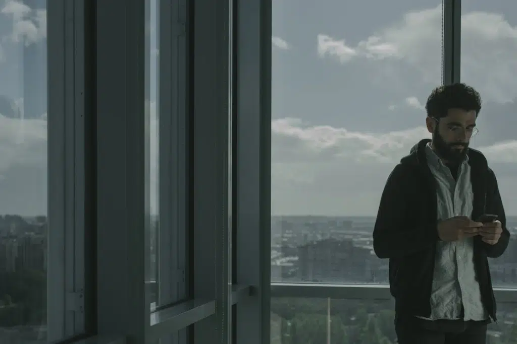 A Man in Black Jacket Standing Near Window