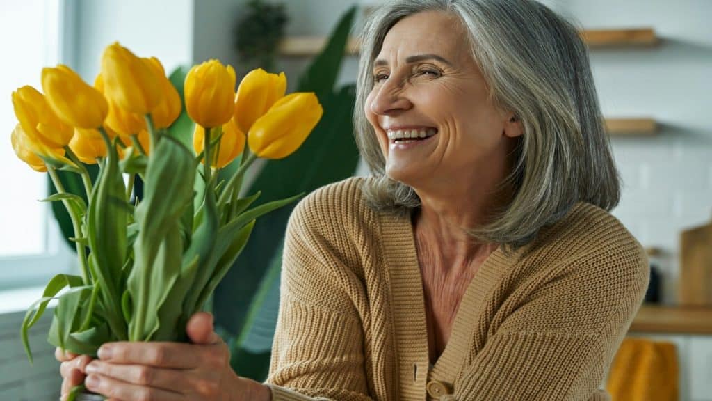 A woman smiling while looking at her tulips