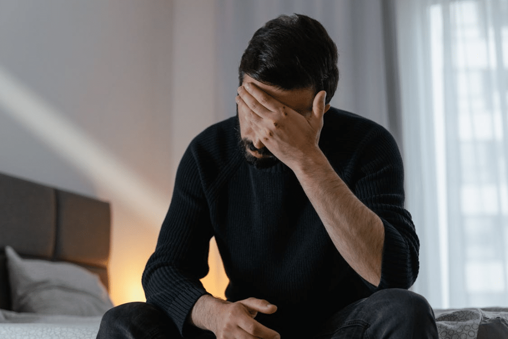 Man in black sweater sitting on bed