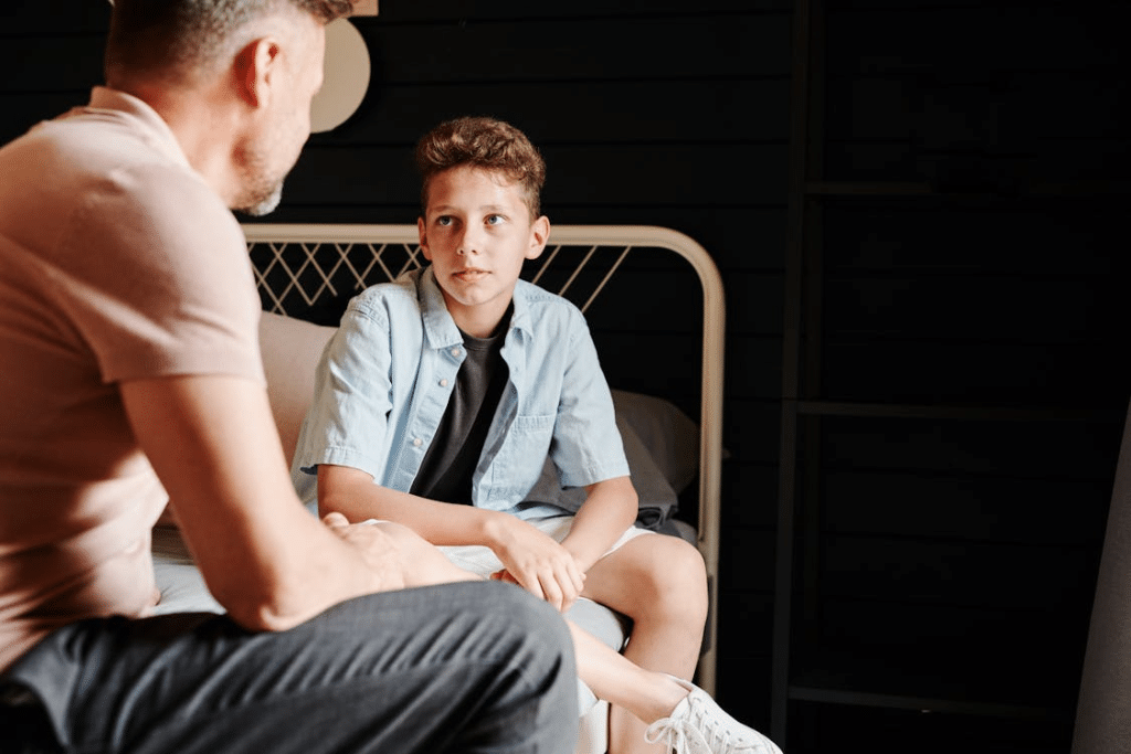 A Father and Son Talking while Sitting on a Bed