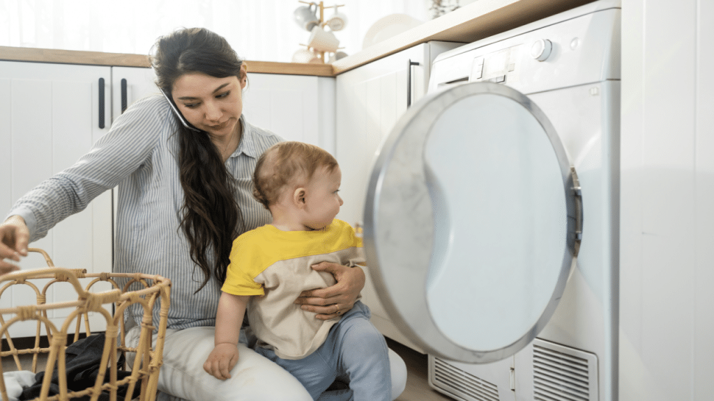 A mom doing the laundry while taking care of her baby