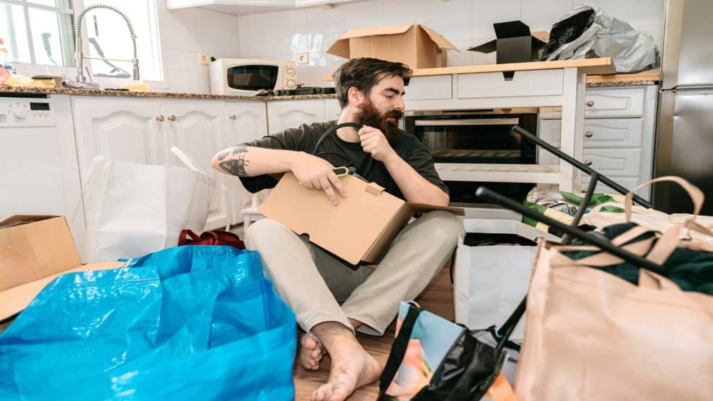 A man sitting in messy kitchen 