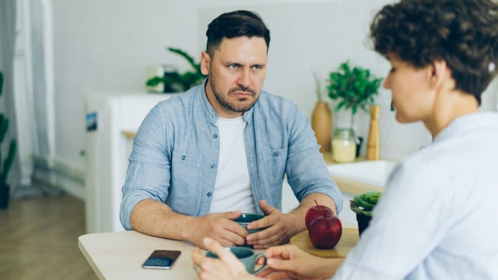 A man sitting at a table talking to a woman.