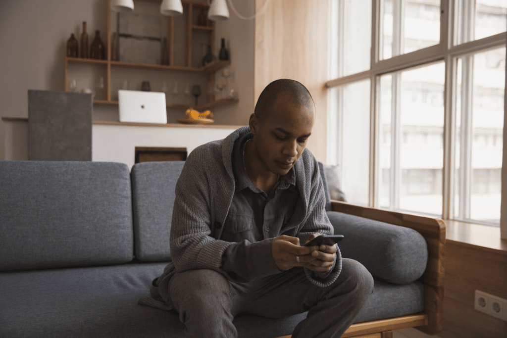 Focused young ethnic male messaging on smartphone at home