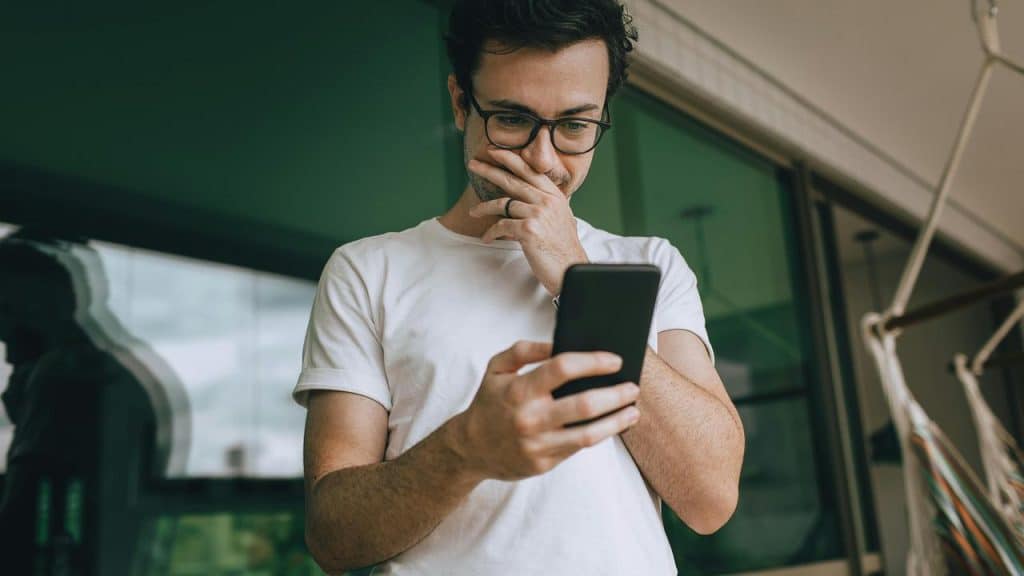 A man looking at his phone with a thoughtful expression.