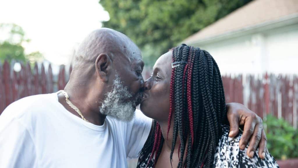 A man and a woman kissing each other outdoors.