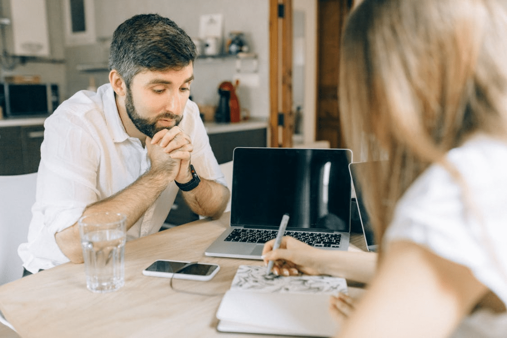 Man in White Long Sleeves Looking Woman While Writing