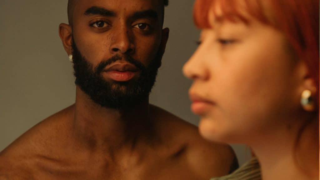 A topless man looking in camera while his wife is looking sideways