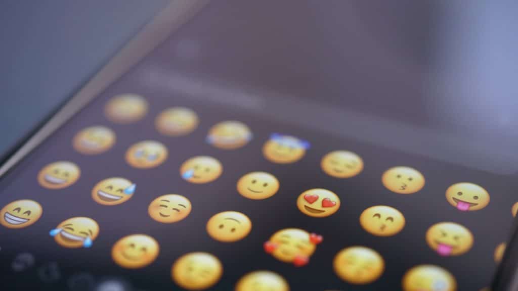 A close-up, shallow depth of field shot of a smartphone screen showing a grid ofย emojisย on the keyboard.