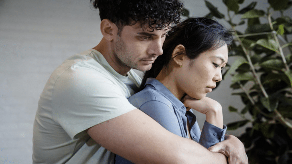 A couple looking sad while hugging