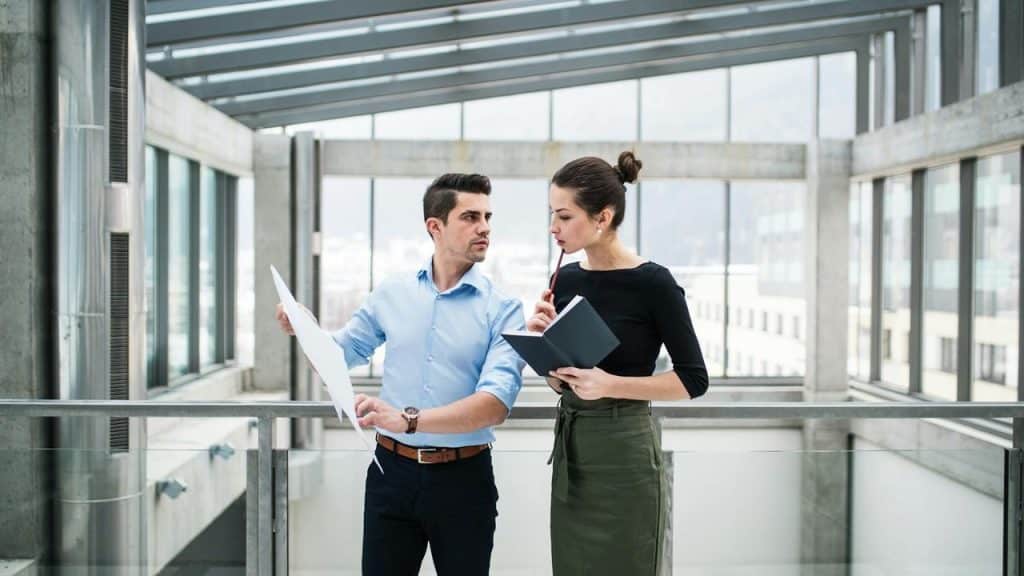 A man and woman discussing documents in a modern office building.