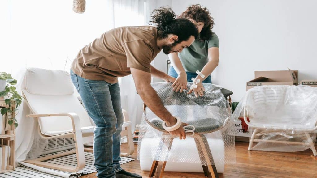A couple covering a chair with bubble wrap