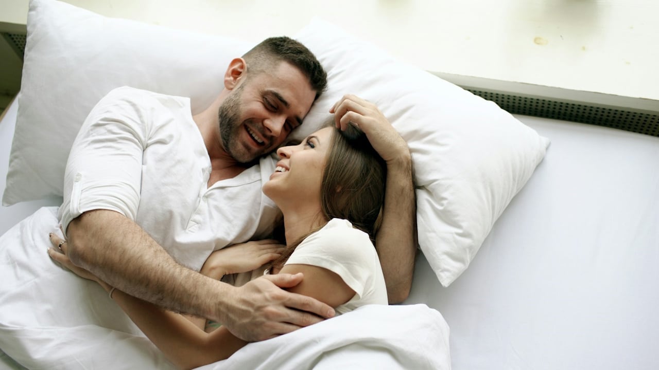 A couple embracing each other in the bed.
