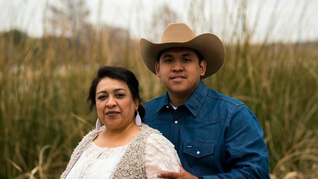 A woman standing with her son, who’s wearing a cowboy hat.