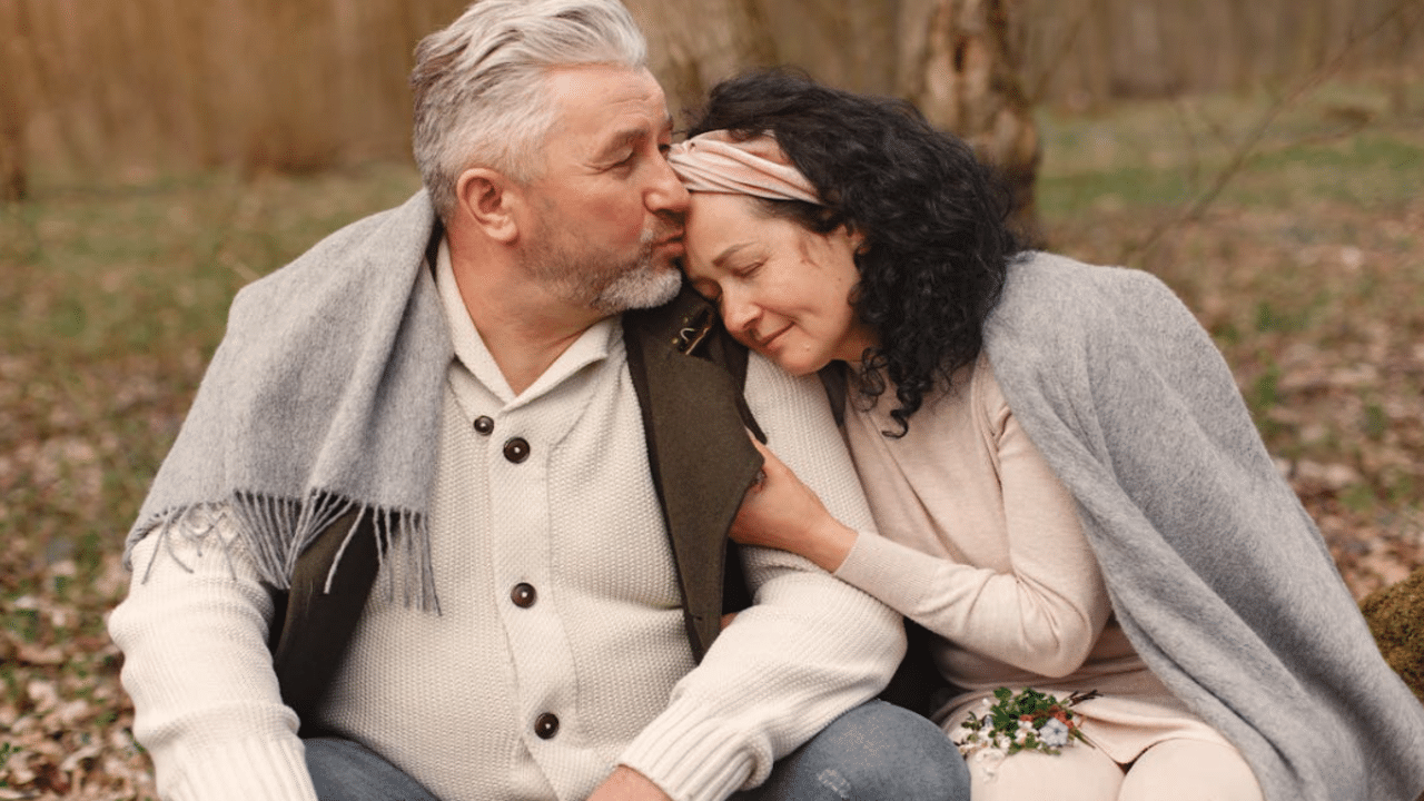 A man giving his wife a forehead kiss