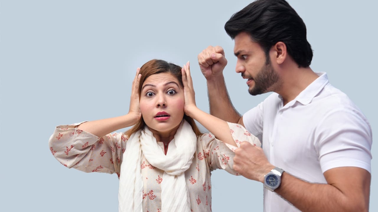 A man shouting at his wife, who is covering her ears with her hands.