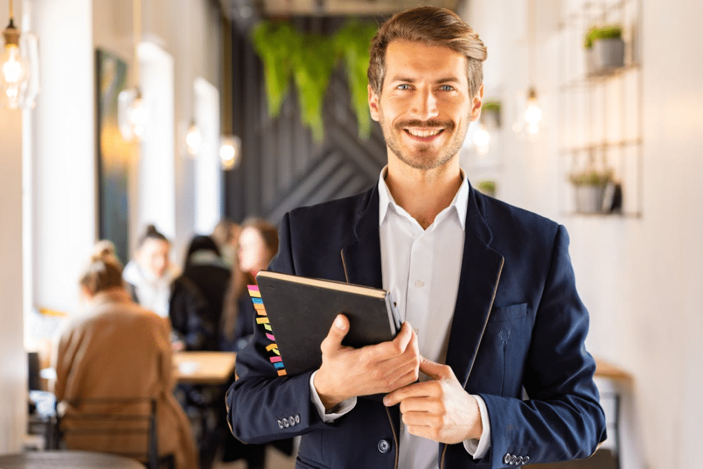 A man smiling while holding a notebook