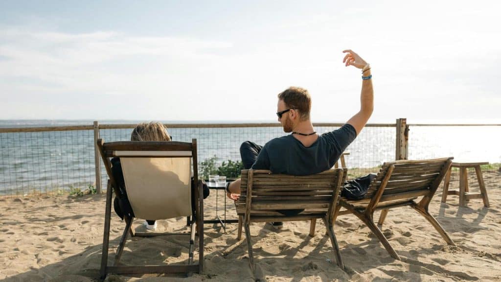A pair lounging on beach chairs by the shoreline.