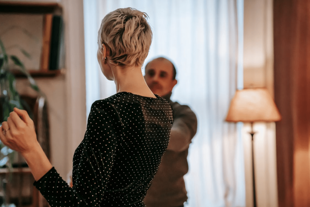 Couple dancing in light room near curtains