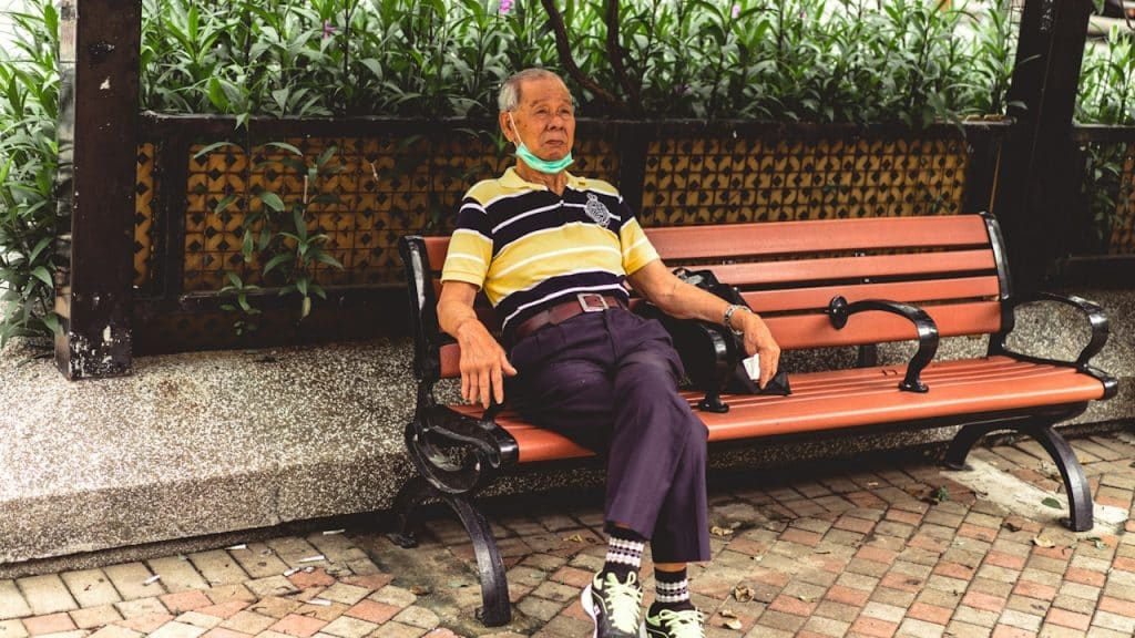 A woman in a blue and yellow striped shirt sitting on a brown bench.