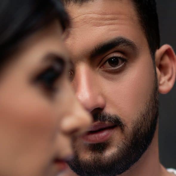 A bearded man looking at a woman intensely.