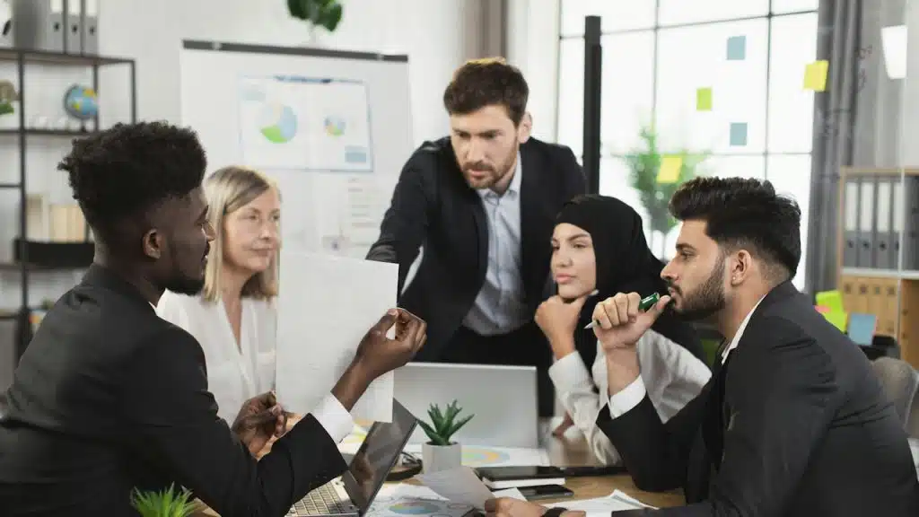 A man leading others in an office during a meeting.