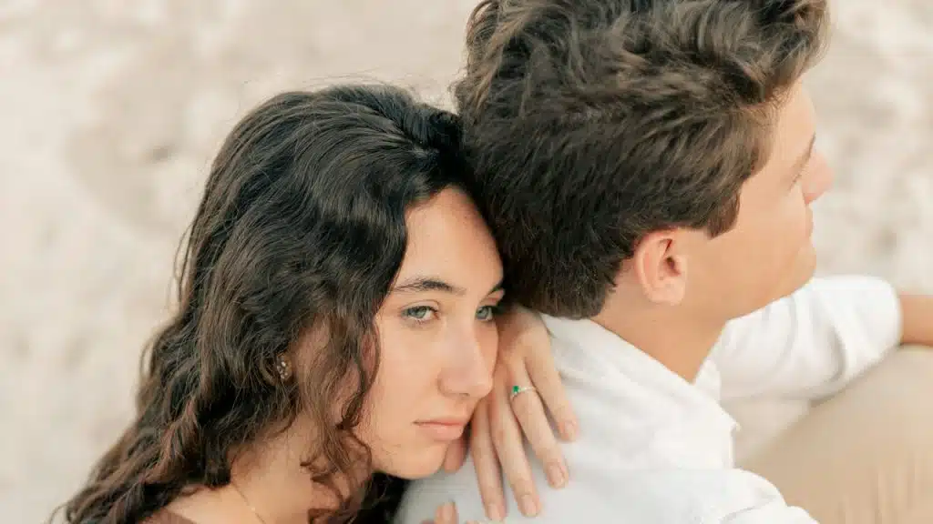 A man and a woman sitting on a beach.