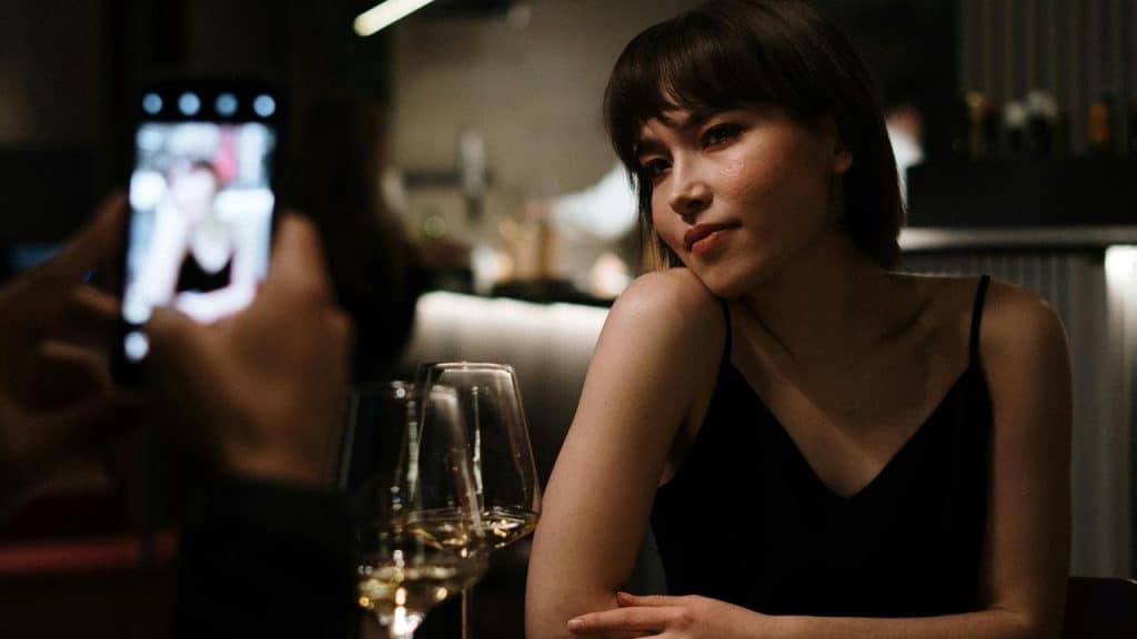 A woman posing at a restaurant table while someone takes her photo.