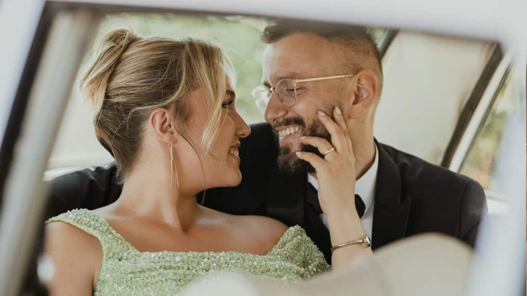 A couple sitting in a car looking at each other.
