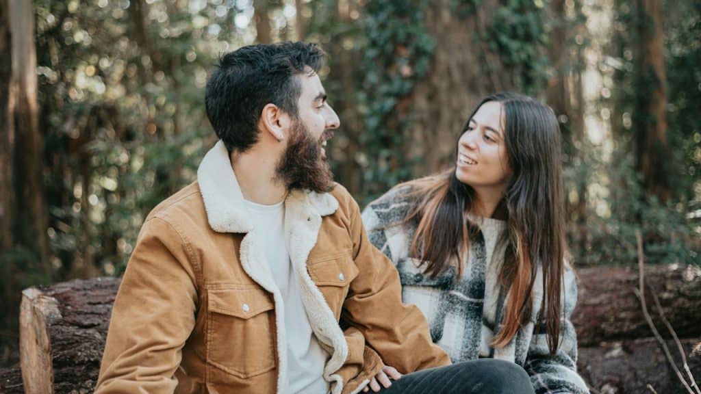 A man and a woman sitting on a wooden bench.