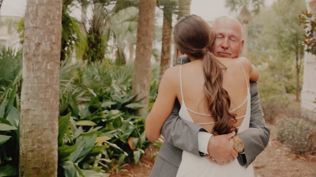 An elderly man is hugging a woman wearing a white gown.
