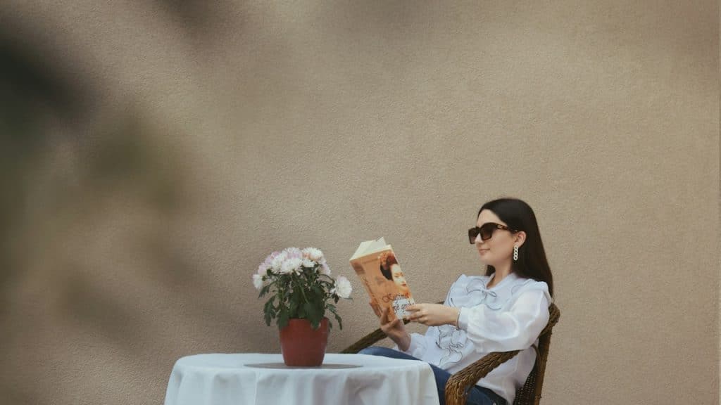 A woman reading a book while sitting at a table.