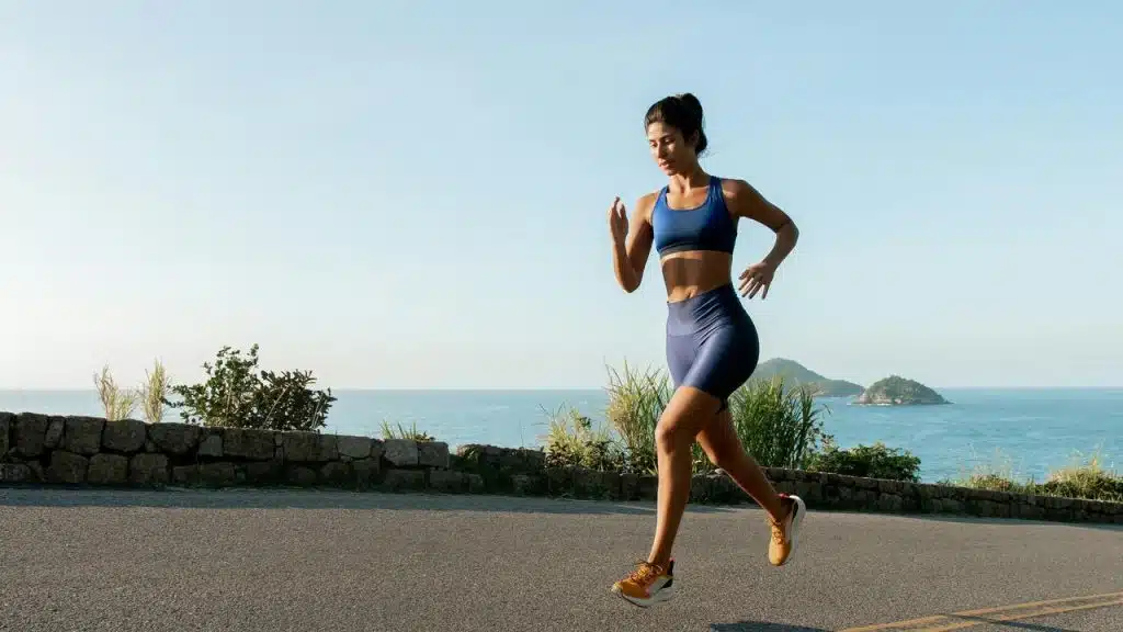 A woman jogging on a seaside road in the morning.