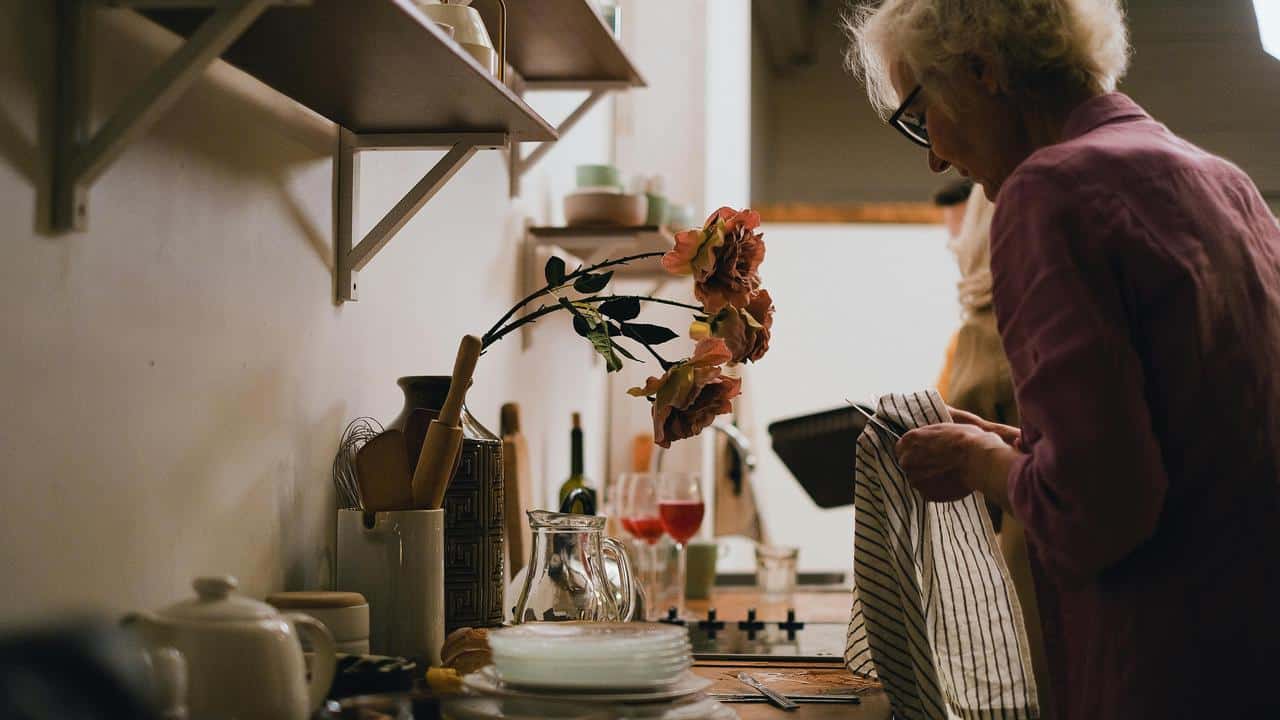 A woman drying dishes in a cozy kitchen.
