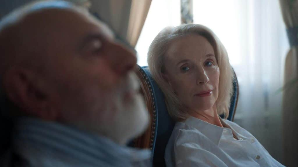 A woman sitting in a chair looking at a man beside her.