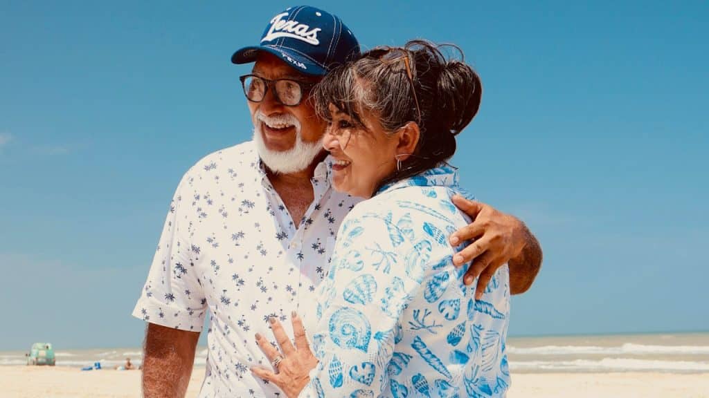 An old couple embracing each other at a sunny beach.