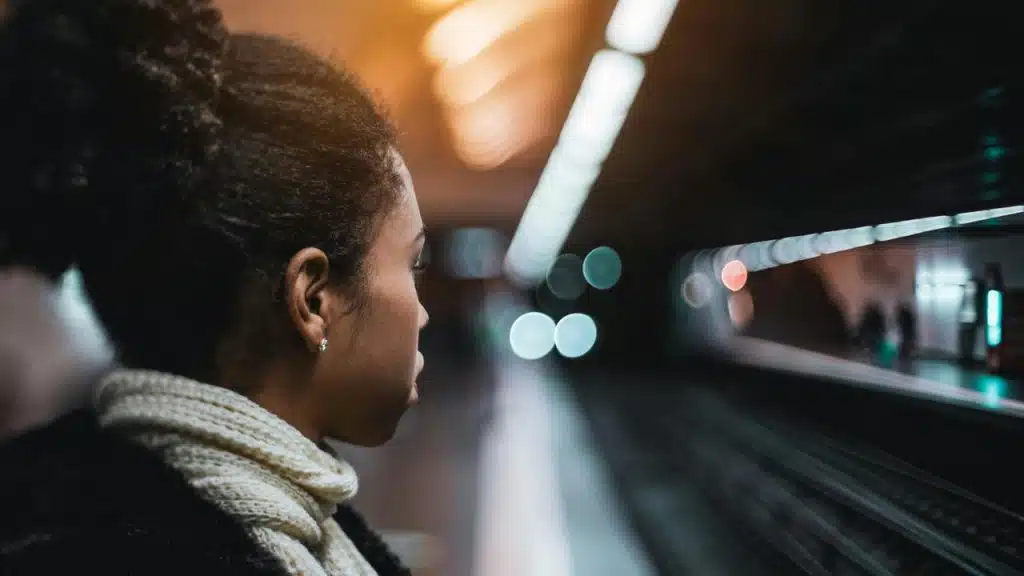 A woman standing on a subway platform looking at the tracks.