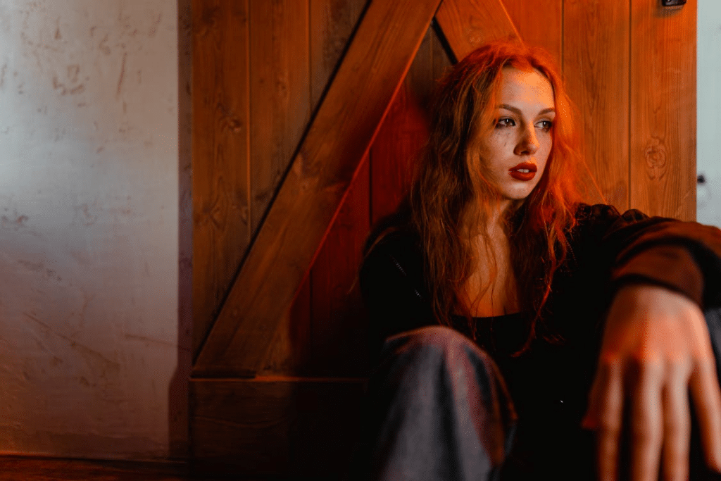 A sad woman leaning on a door
