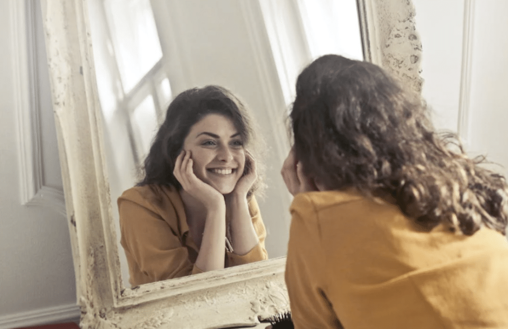 A woman smiling at herself in the mirror 