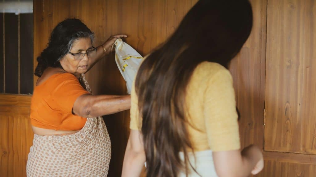 A mother-in-law helps her daughter-in-law in wearing a sari.